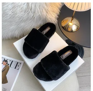 Top view of black plush platform slippers on a box next to a lamp and magazines