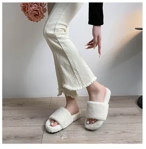 Close-up of off-white faux fur slide slippers with thick soles on model in cozy setting