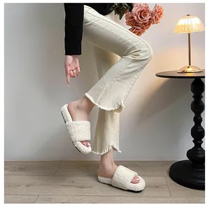 Detail of plush cream faux fur platform slippers with a thick black sole on wooden floor