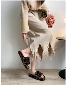 Close-up of leopard print faux fur slide sandals on a model wearing a fringed knit skirt