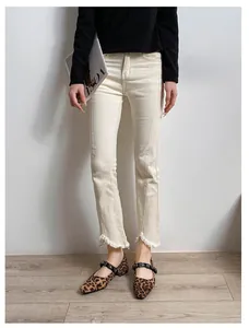 Detalle de vaqueros ajustados color blanco roto con costura frontal y bajo deshilachado
