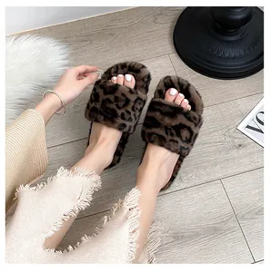 Top-down view of leopard print faux fur slides worn with denim on a wooden floor