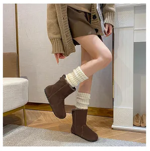 Dunkelbraune Wildleder-Stiefeletten mit cremefarbenen Strickstulpen in gemütlicher Szene