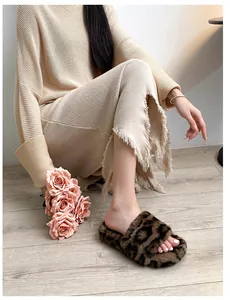 Close-up of leopard print plush slippers worn on wood floor with warm home ambiance