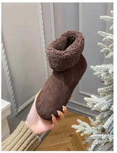 Nahaufnahme brauner Leder-Schneestiefel mit warmem Plüschrand und festlicher Dekoration