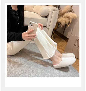 Detailed side view of white plush faux fur mules with stylish beige flared trousers