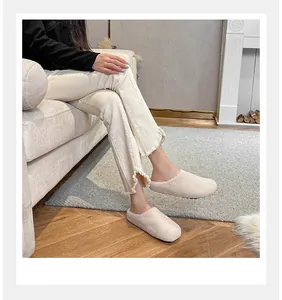 Detail of warm beige plush mules styled with fringe jeans in a cozy home setting