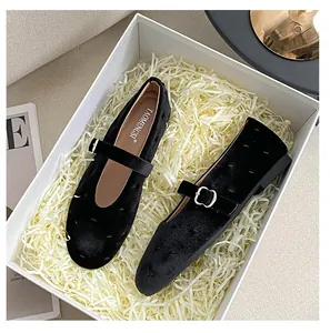 Détail de ballerines Mary Jane en velours noir avec boucle métallique dans un coffret