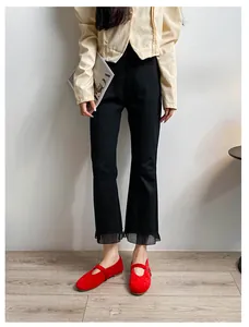 Détail d'un pantalon évasé noir avec ourlet en tulle plissé et chaussures Mary Jane rouges