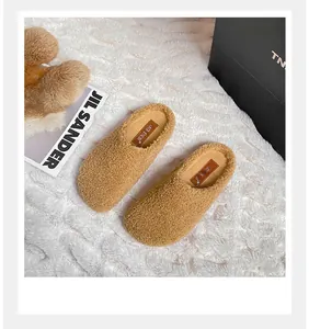 Close-up of brown teddy fur clogs with warm fleece lining on a cozy white faux fur rug