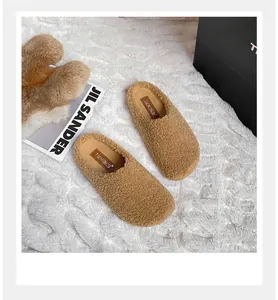 Detail macro view of warm camel teddy fleece mules with soft plush texture and leather label