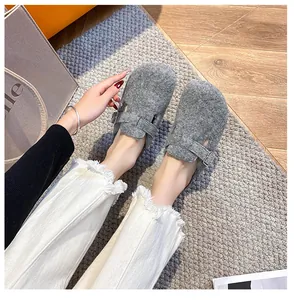 Detailaufnahme grauer Filz-Clogs mit verstellbarem Riemen auf gemütlichem Teppich