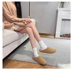 Close-up of cozy camel faux shearling mules with socks in a warm home setting