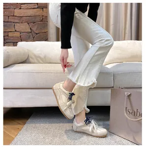 Close-up of beige suede training sneakers with stylish dual-color navy and white laces