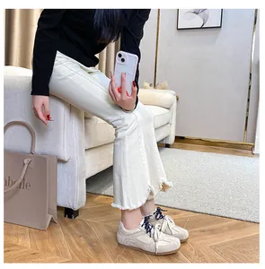 Retro cream trainers with suede panels and black laces worn with flared trousers