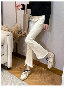 Detail of off-white flare jeans with raw hem and patterned laces on casual sneakers