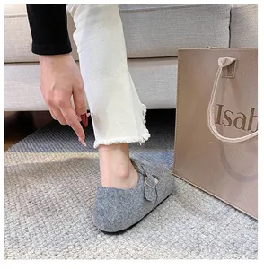 Gray felt mule shoe detail with silver metal buckle on cozy woven carpet background
