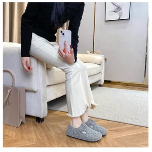 Detail of grey felt clogs with metal buckle and warm lining on a cozy home background