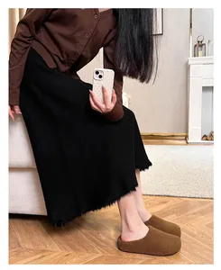 Detailed view of the fuzzy slippers with fur lining and frayed hem of a black skirt