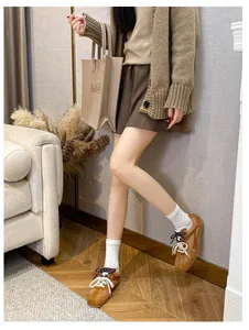 Retro brown sneakers with dual-color laces styled with socks and a pleated skirt