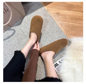 Brown fleece mule slippers for women on rug background for a warm home atmosphere