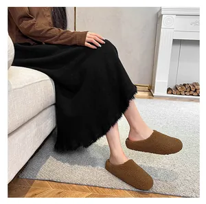 Brown suede winter slippers with warm faux fur lining worn with a long black skirt