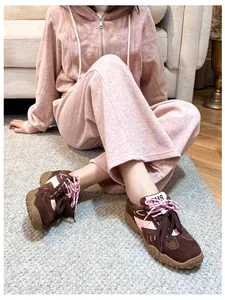 Dettaglio di sneaker scamosciate marrone e rosa con tuta sportiva in pile rosa