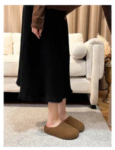 Close-up of brown plush mule slippers worn with black skirt in cozy interior setting