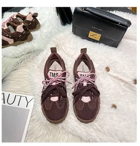 Vista dall'alto di sneakers in pelle retrò con dettagli rosa e doppi lacci su tappeto
