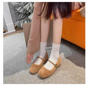 Detail van bruine pluche Mary Jane-schoenen met leren bandje en gouden gesp in winterse sfeer