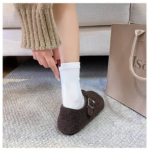 Detail view of dark brown wool felt mule shoes with adjustable metal buckle on a cozy rug