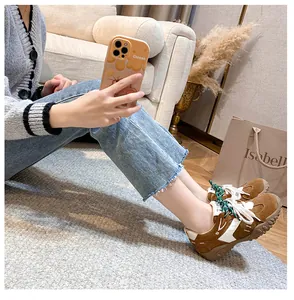 Dettaglio di sneaker retrò in pelle con lacci verdi intrecciati e suole platform marroni