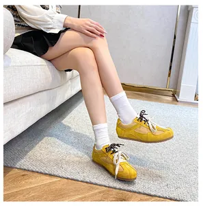 Detail of yellow suede casual sneakers with dual laces and brown rubber sole on grey rug