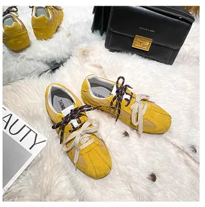 Top view of yellow leather sneakers with dual laces on a white plush carpet background