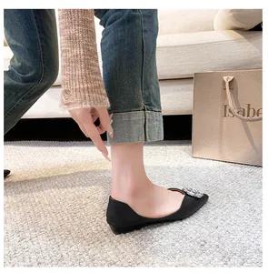 Elegant side view of black pointed-toe flat shoes with a large sparkling rhinestone flower