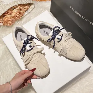 Beige suede sneakers with double laces and TAOMEN branding on a textured cream background