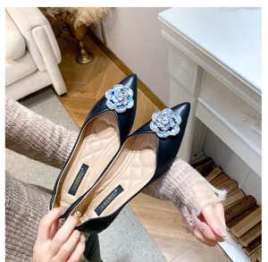 Detail of black pointed toe flat with sparkling rhinestone flower and quilted beige insole
