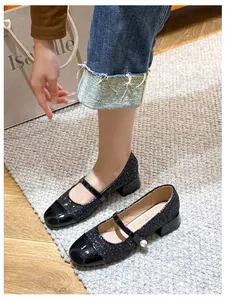 Detalle de zapato Mary Jane de lentejuelas negras con tacón ancho y hebilla de perla