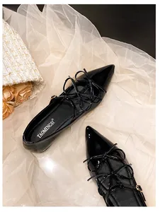 Close-up of black pointed toe flat shoes with layered bow straps and patent finish