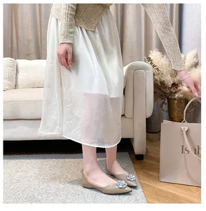 Close-up of beige pointed toe flats featuring a sparkling rhinestone flower buckle detail