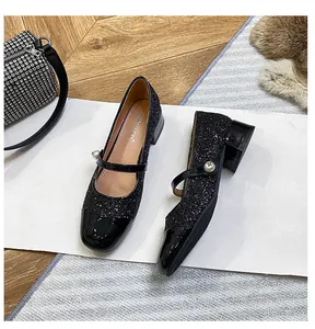 Detalle de Mary Janes de lentejuelas negras con punta de charol y correa de perlas