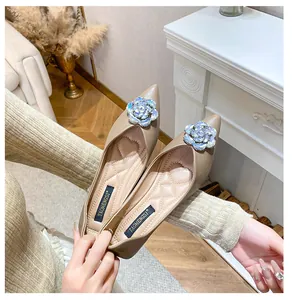 Detailed close-up of pointed-toe flats with sparkling blue crystal flower ornament
