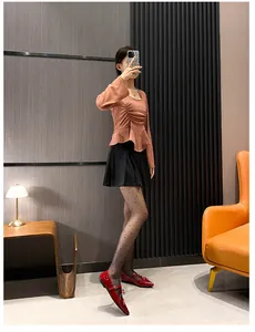 Fashionable outfit featuring red pointed-toe flats, pleated skirt, and terracotta top