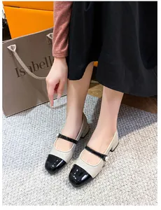 Detalle de los zapatos Mary Jane plateados con punta de charol negro y una correa de perla