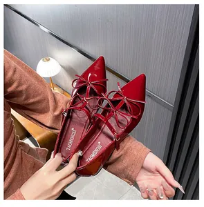 Close-up of deep red patent leather pointed flats with bow detail and adjustable ankle strap