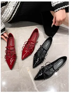 Close-up of glossy pointed-toe Mary Janes with double bows and T-straps on marble floor