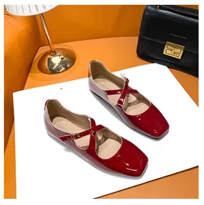Close-up of red patent leather Mary Jane flats with square toe and cross strap details