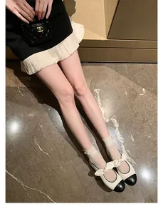 Top view of two-tone Mary Jane flats featuring a black cap toe and delicate bow detail