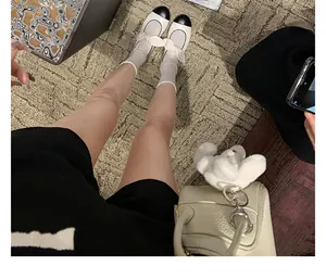 POV shot of black and white bow Mary Jane flats on a beige textured carpet