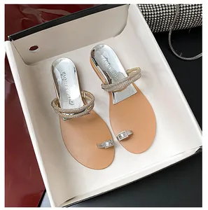 Detailed view of women's flat toe-loop sandals featuring sparkling rhinestone buckles